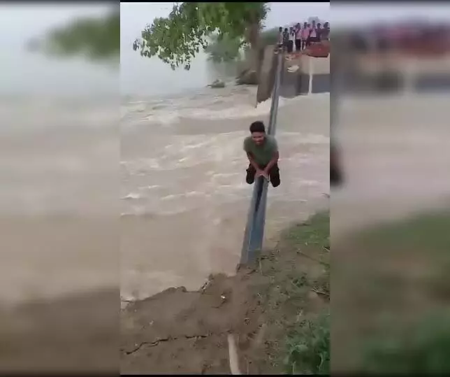 बाढ़ के पानी के बीच युवक ने बनाई रील, पाइप के सहारे पार की टूटी सड़क