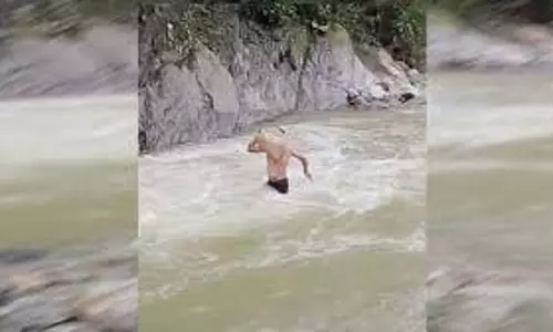 कंधे पर सामान लेकर नदी पार करता युवक, डीएम ने दिए जांच के आदेश कंधे पर सामान लेकर नदी पार करता युवक, डीएम ने दिए जांच के आदेश