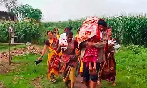 ख़राब सड़क: माँ बच्चे को कंधे पर उठाकर ले जा रही ख़राब सड़क: माँ बच्चे को कंधे पर उठाकर ले जा रही