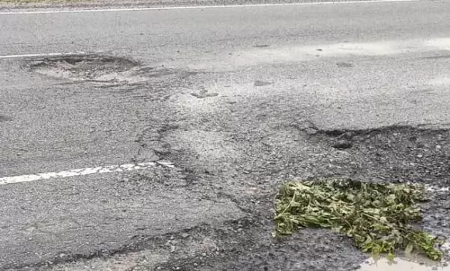 सड़क में पड़े गड्ढों की मरम्मत कर रहे युवा