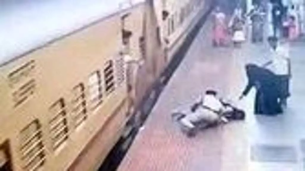 एक गार्ड ने एक जवान औरत को बचाया जो चलती ट्रेन में चढ़ने की कोशिश करते समय गिर गई थी एक गार्ड ने एक जवान औरत को बचाया जो चलती ट्रेन में चढ़ने की कोशिश करते समय गिर गई थी