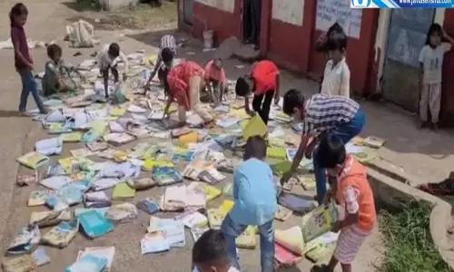 बारिश से भीगीं बच्चों की किताबें खुले मैदान में सुखाने को मजबूर
